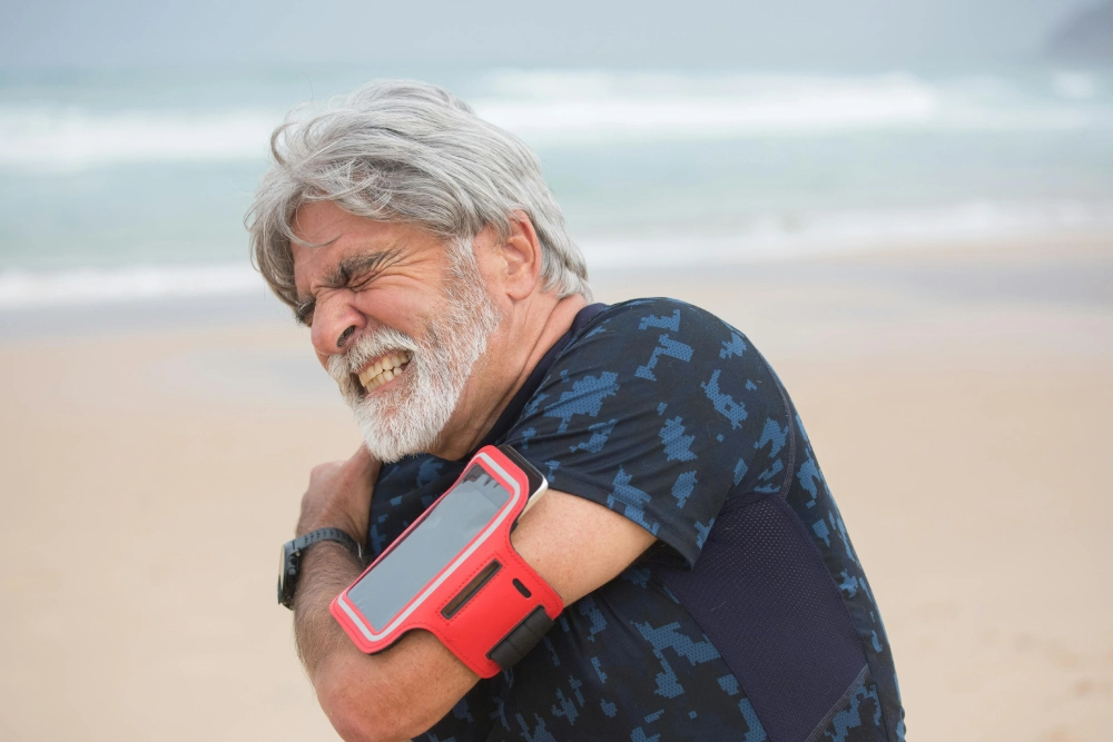 A man with grey hair and beard holding onto his phone.